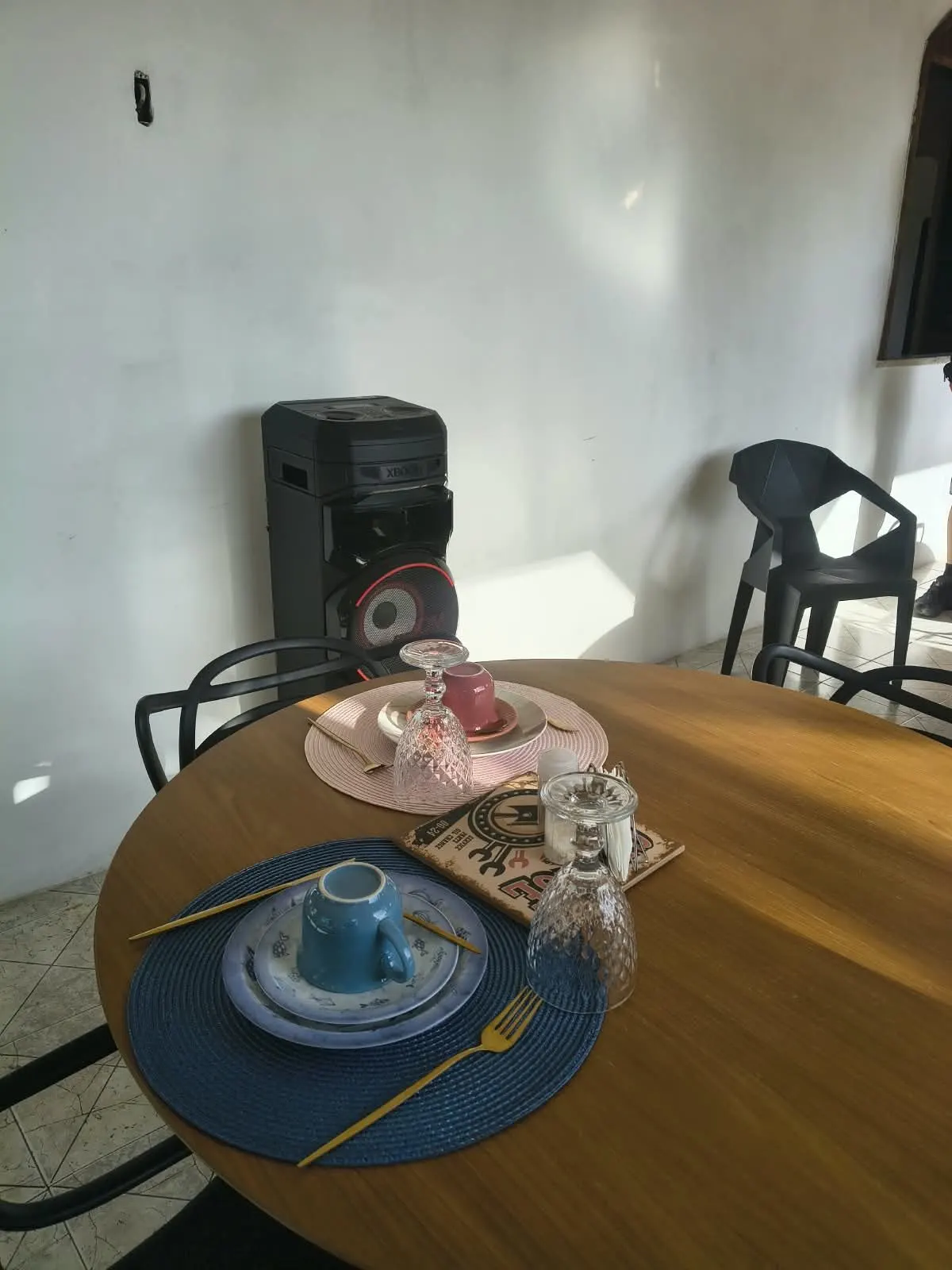 Mesa de café da manhã posta com louças coloridas e talheres dourados