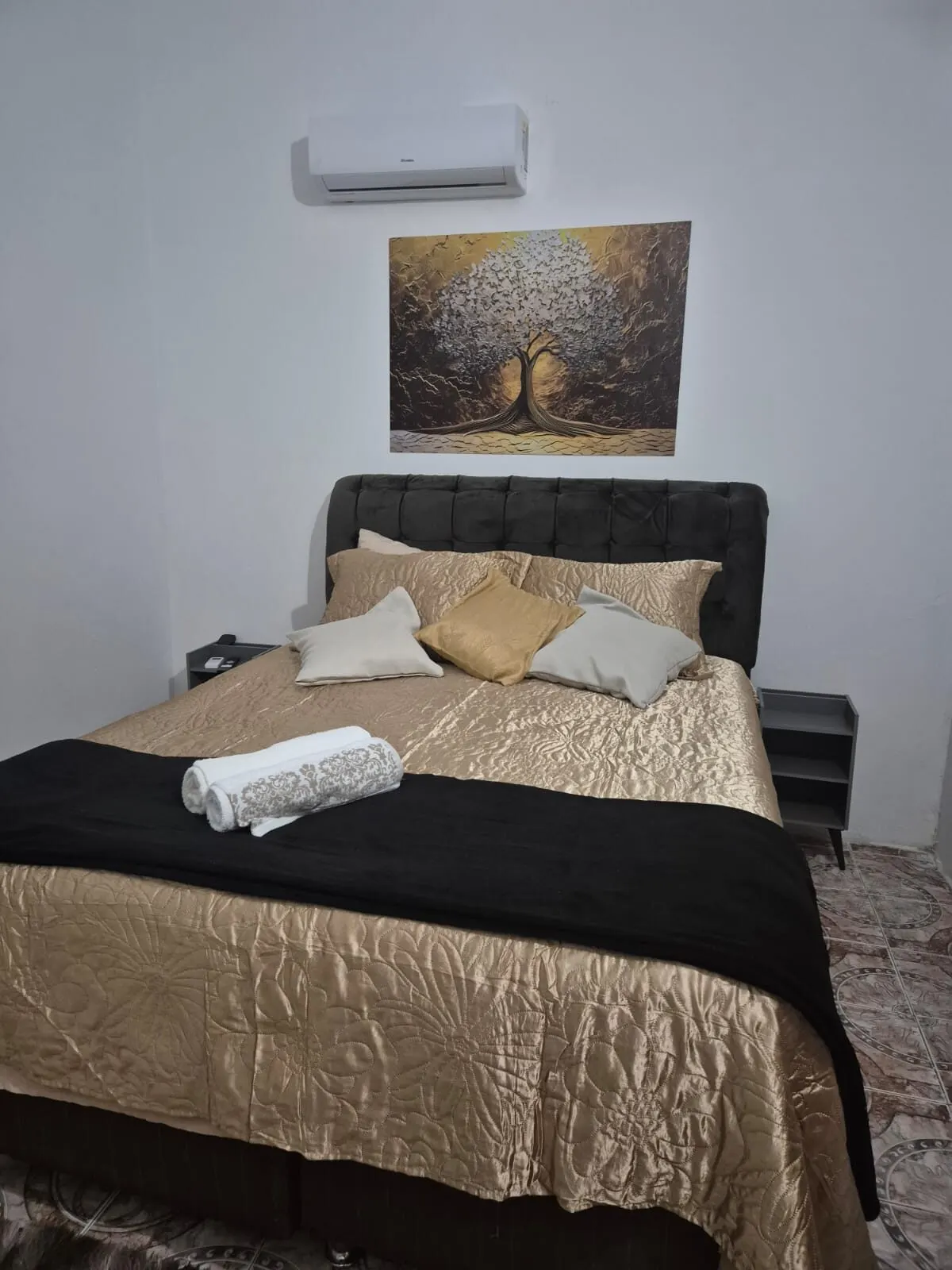 Suíte Dourada com ar-condicionado split sobre a cama